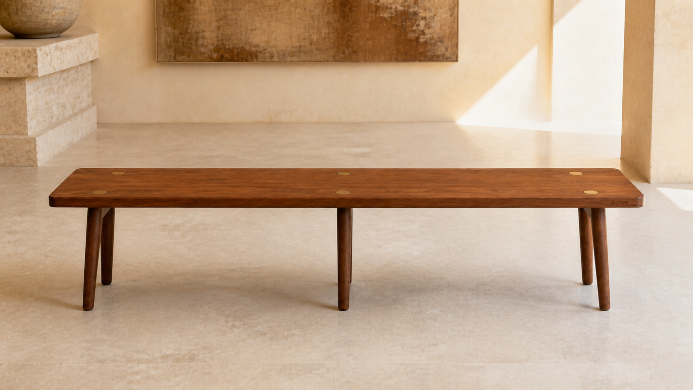 AUTHË v2 panoramic header — 2600 millimetre Pin Bench in a light gallery, showing one walnut top, six tapered legs and six bronze caps